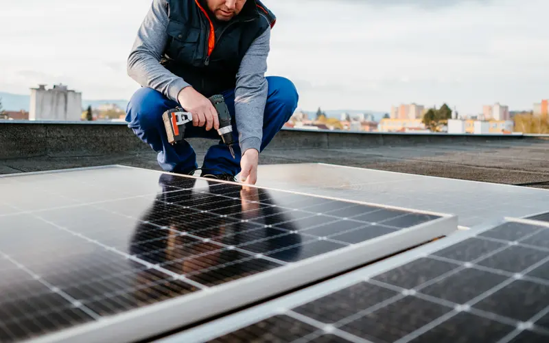 Instalador fixando módulos fotovoltaicos no telhado de uma residência