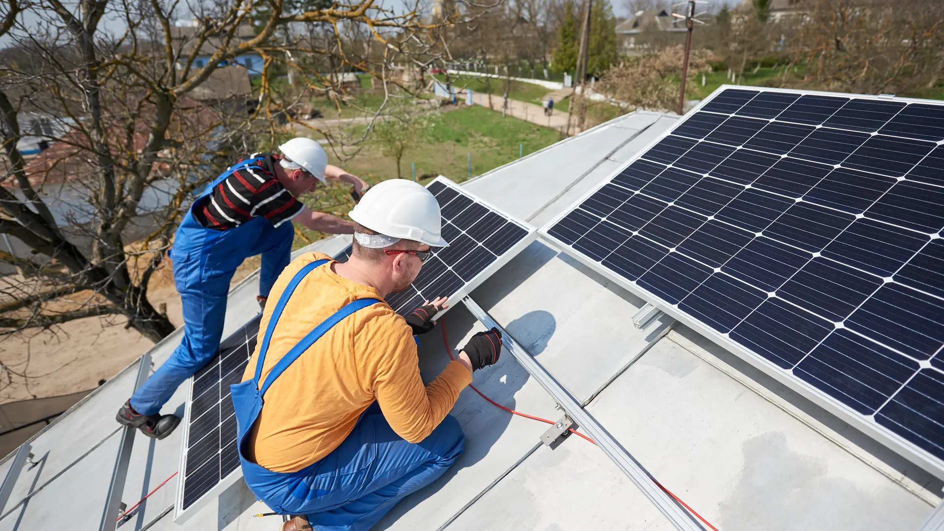 Equipe de instaladores fixando módulos fotovoltaicos no telhado de uma casa