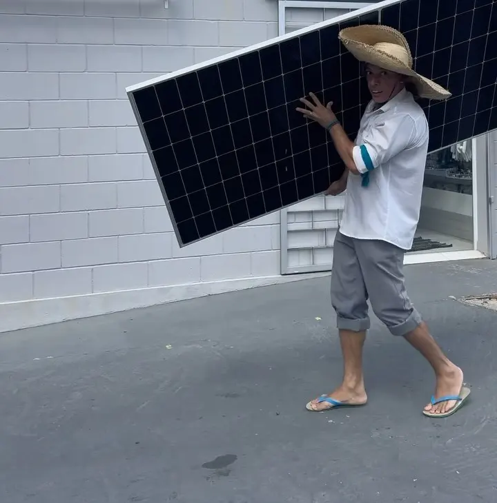 Colaborador da Lumiar carregando um módulo solar em frente à loja, no Centro de Cajati